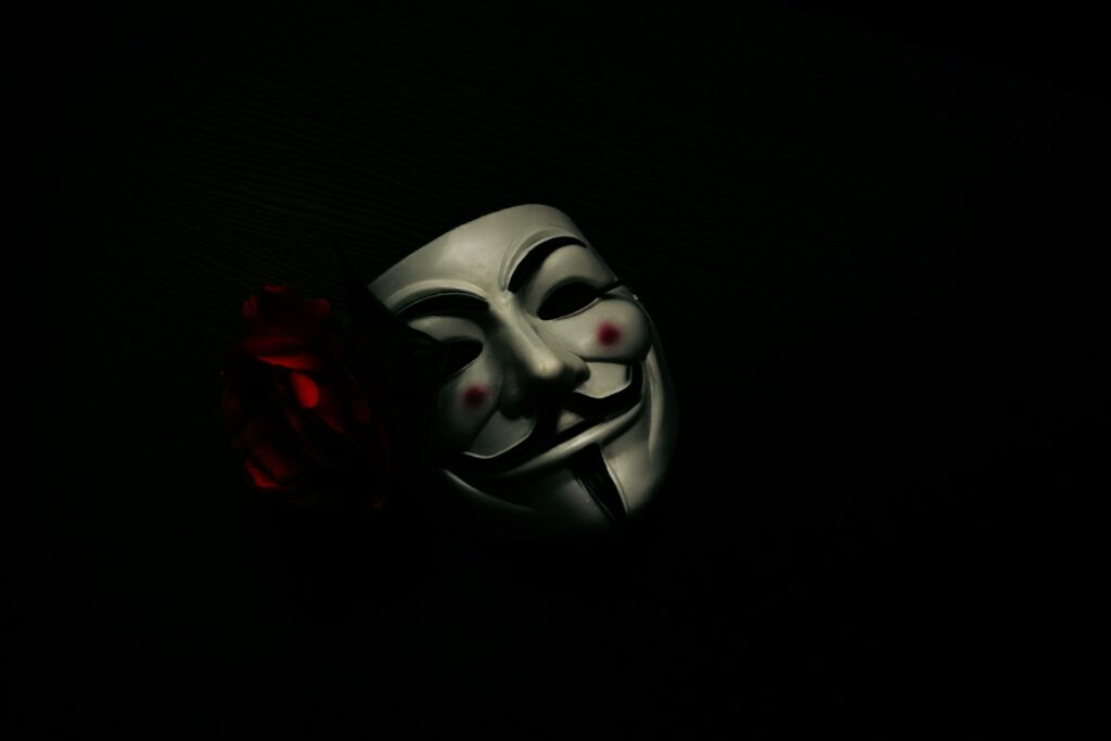 a white mask and a red rose on a black background
