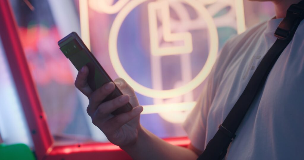 a man holding a cell phone in front of a neon sign